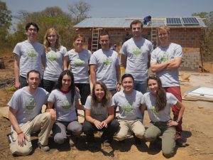 Henry Louie (top row, third from right) and his KiloWatts for Humanity volunteers stand in front of a solar-powered energy kiosk they built in Zambia. 